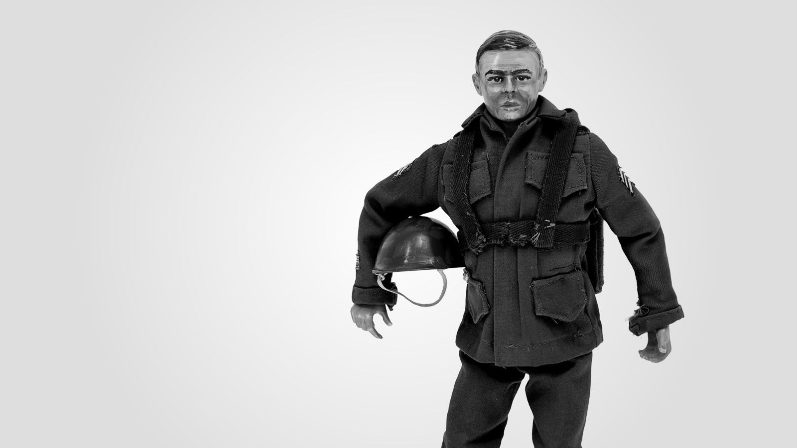 A detailed doll of a paratrooper standing at ease, with his helmet tucked under one arm