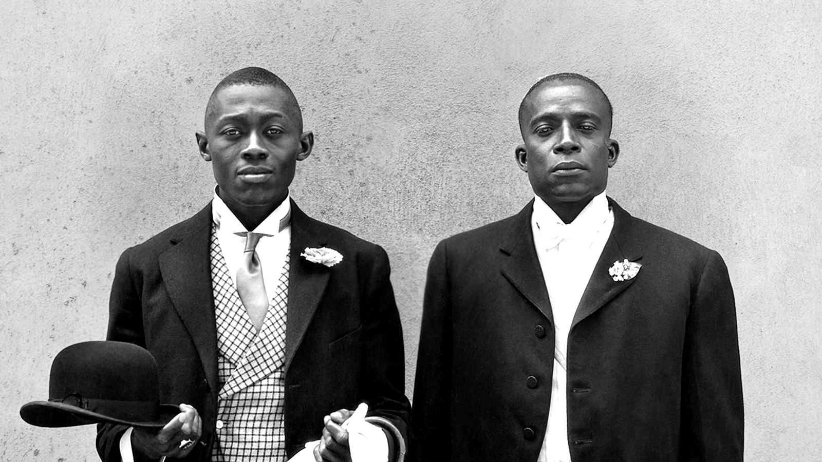 Two black men standing side-by-side in formal suits